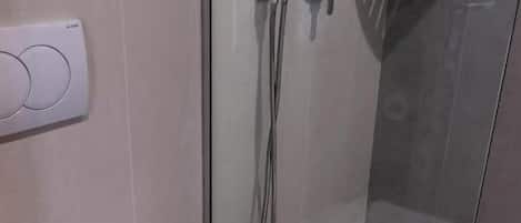 Ein modernes Badezimmer mit einer Duschkabine aus Glas, einer Toilette mit weißem Handtuch und einer wandmontierten Bedienkonsole.