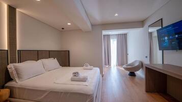 A modern hotel room with a large bed, a desk, and a television on the wall.