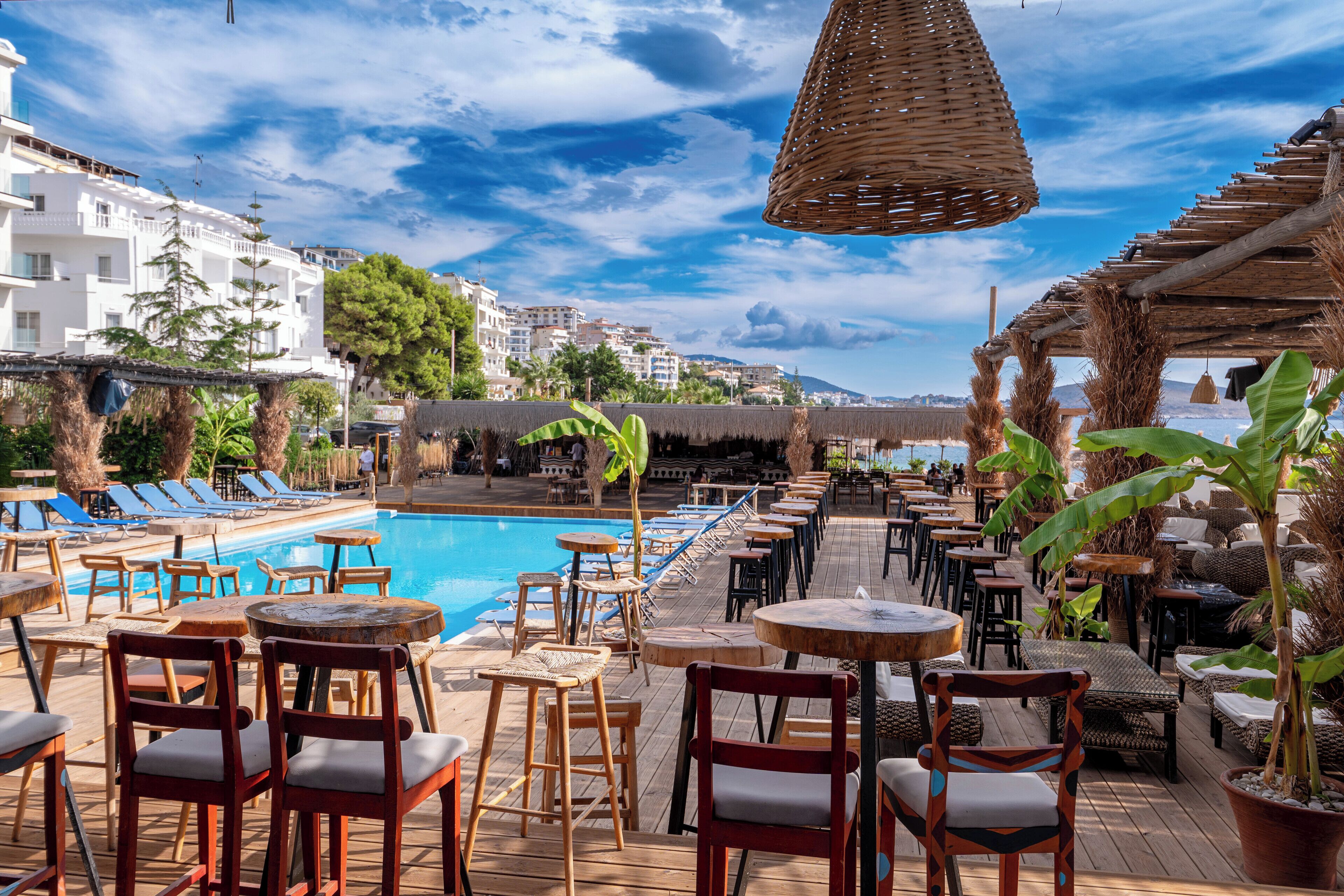 A poolside area with lounge chairs, tables, and umbrellas.