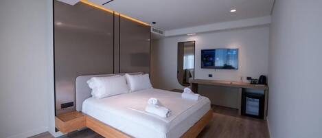 Una habitación de hotel moderna con una cama de madera, un escritorio y un televisor de pantalla plana.