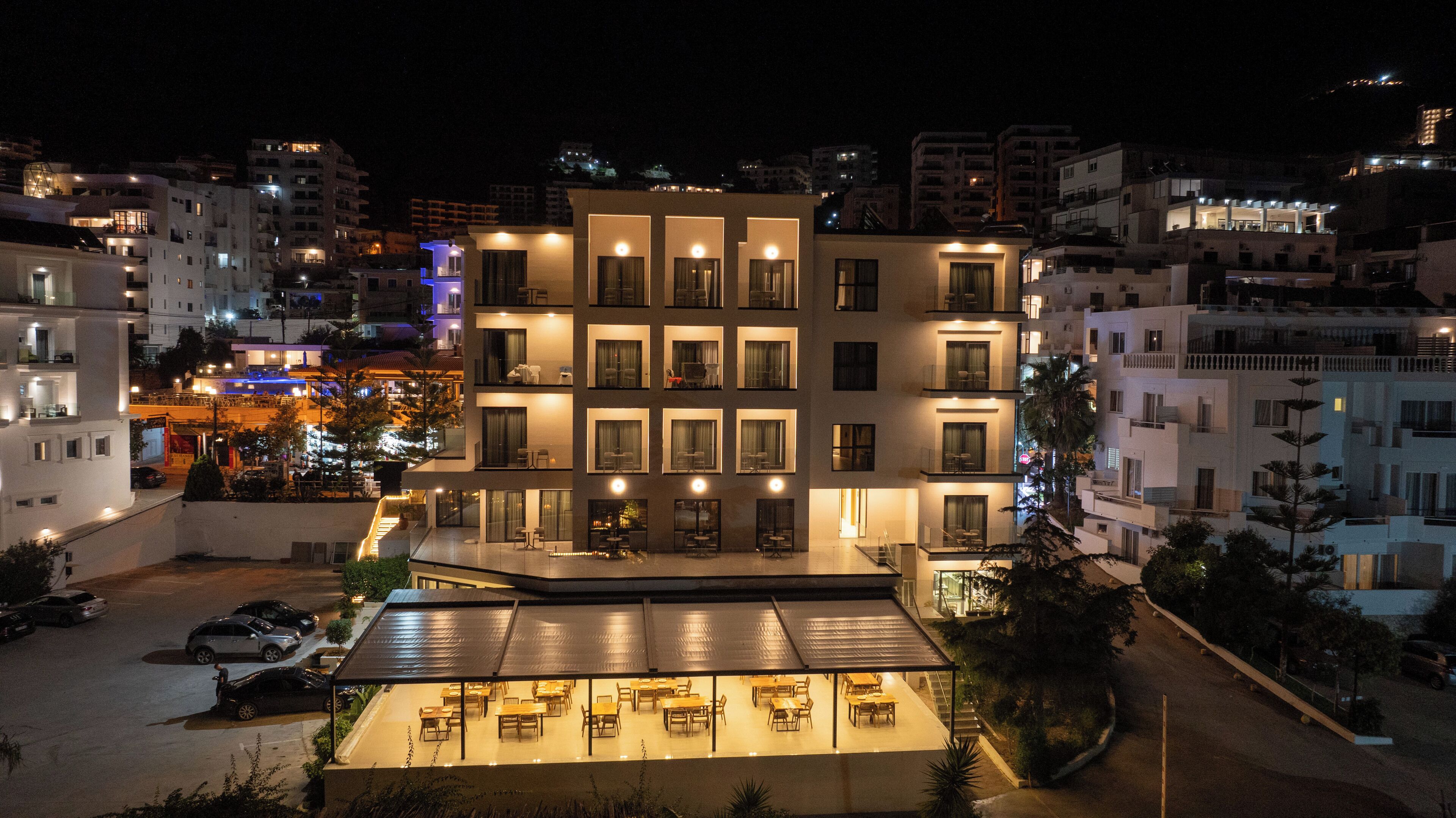 Een meerlaags hotel met een terras voor uiteten op de begane grond en meerdere balkons.