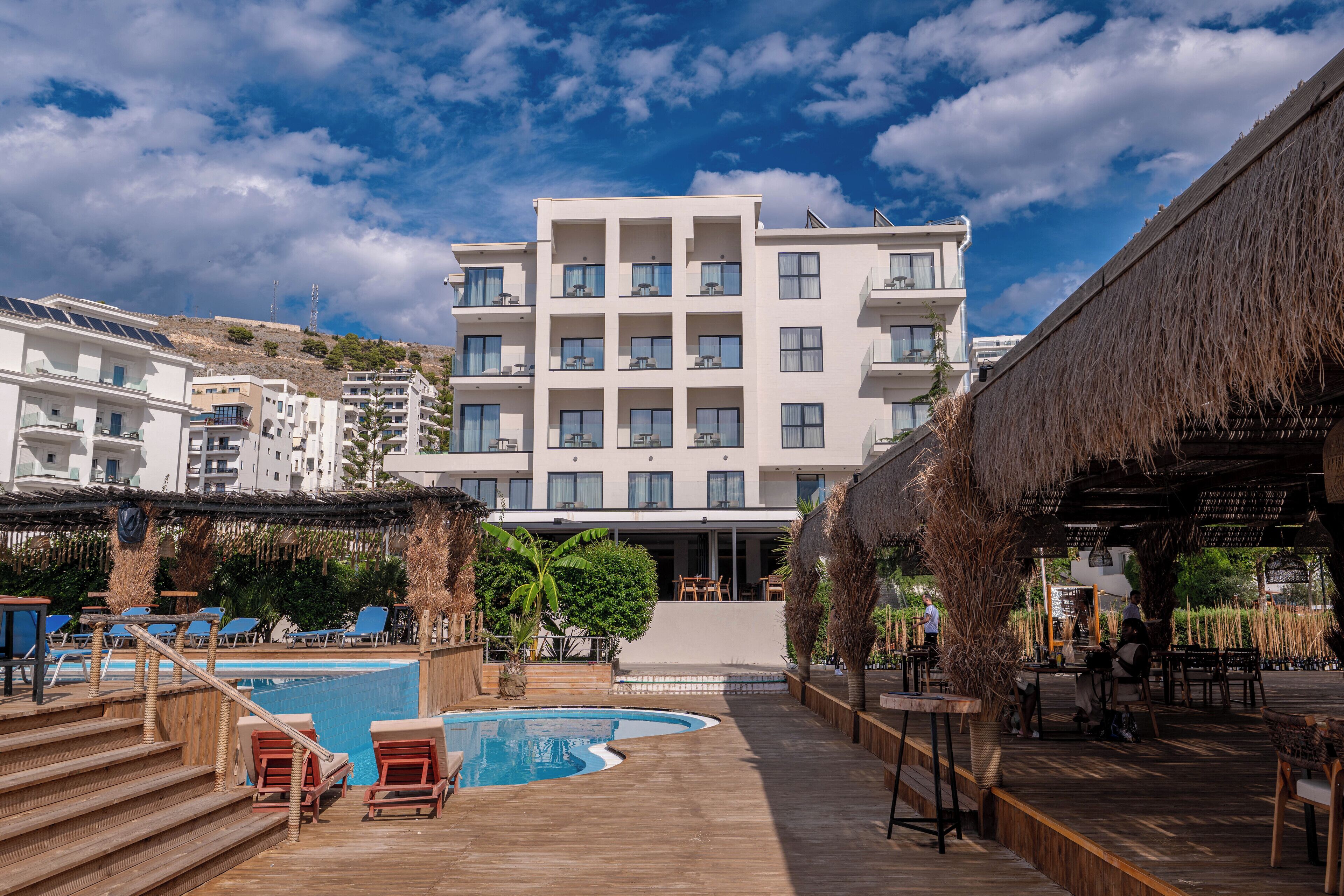A modern hotel with a pool area, outdoor seating, and a view of the surrounding buildings.