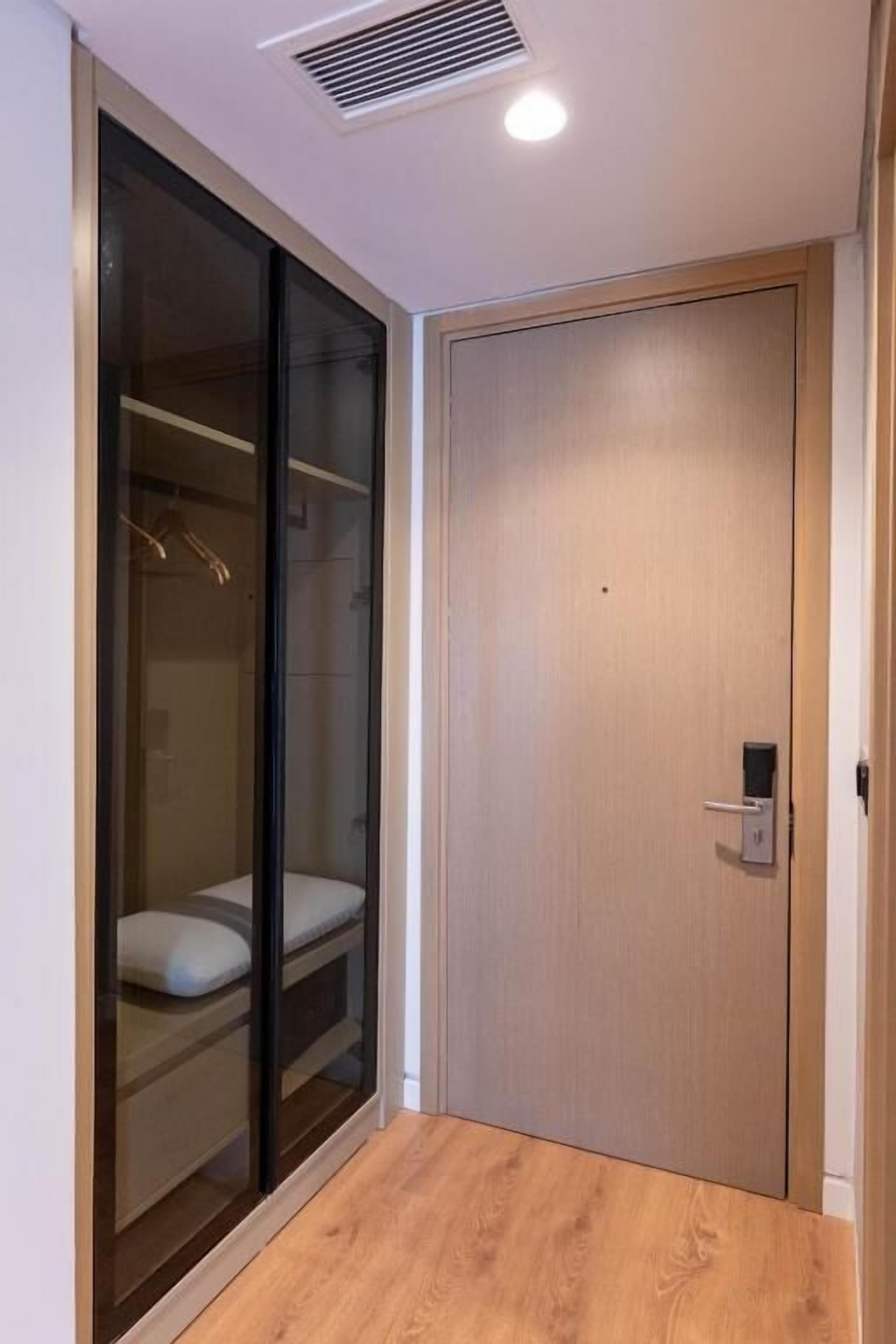 Ein Zimmer mit Schiebetüren, einem Holzfußboden und einem Lichtschalter an der Wand.