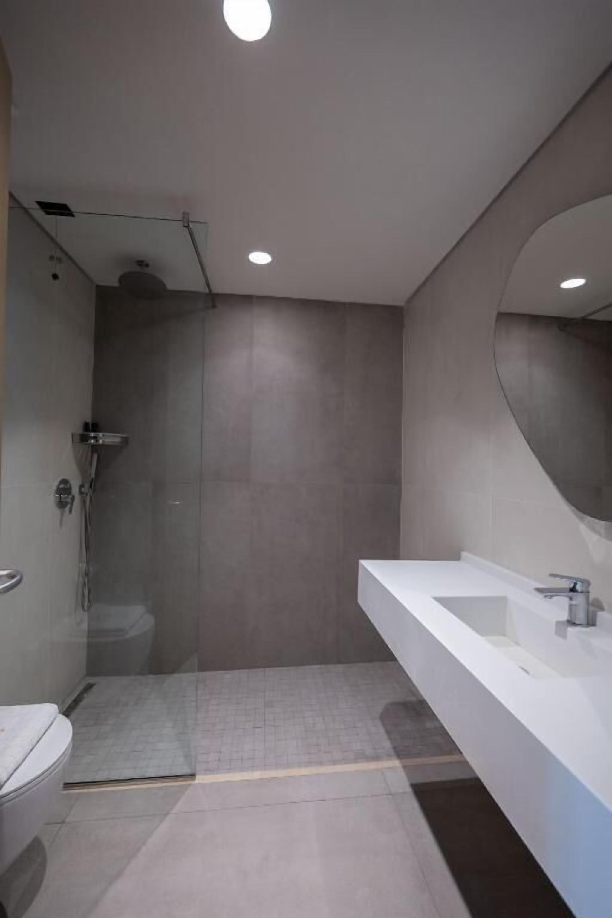 A modern bathroom with a glass-enclosed shower, a white sink, and a large mirror.