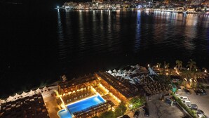 A waterfront hotel with a pool, outdoor seating, and a view of the city at night. - Grand Hotel Saranda (Sarandë)
