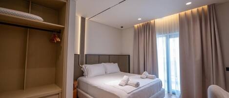 A modern hotel room with a large bed, a wardrobe, and a seating area.