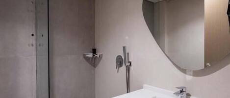 A modern bathroom with a glass shower enclosure, a white vanity, and a large mirror.