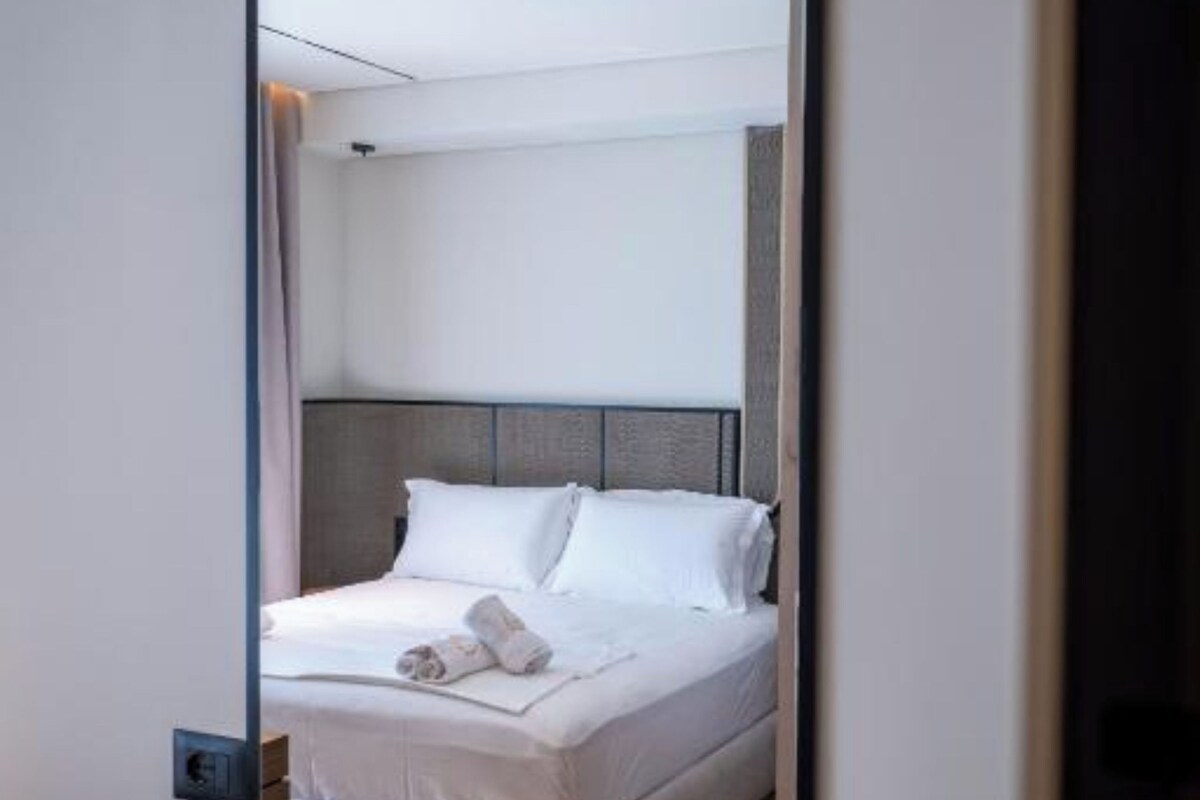 Un dormitorio con cama, cabecera y espejo.