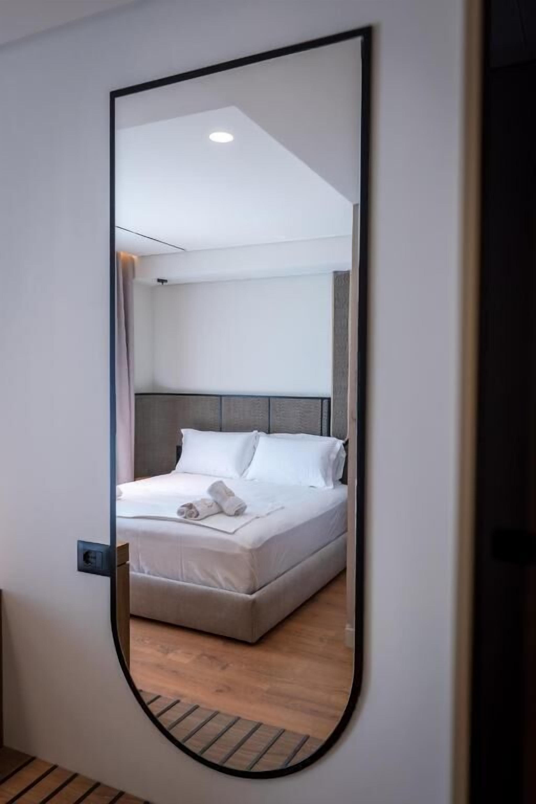 A bedroom with a bed, a headboard, and a mirror.
