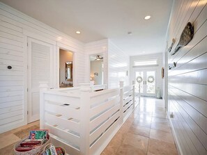 A hallway with a white reception desk, a ceiling fan, and a door leading to a room with a view.