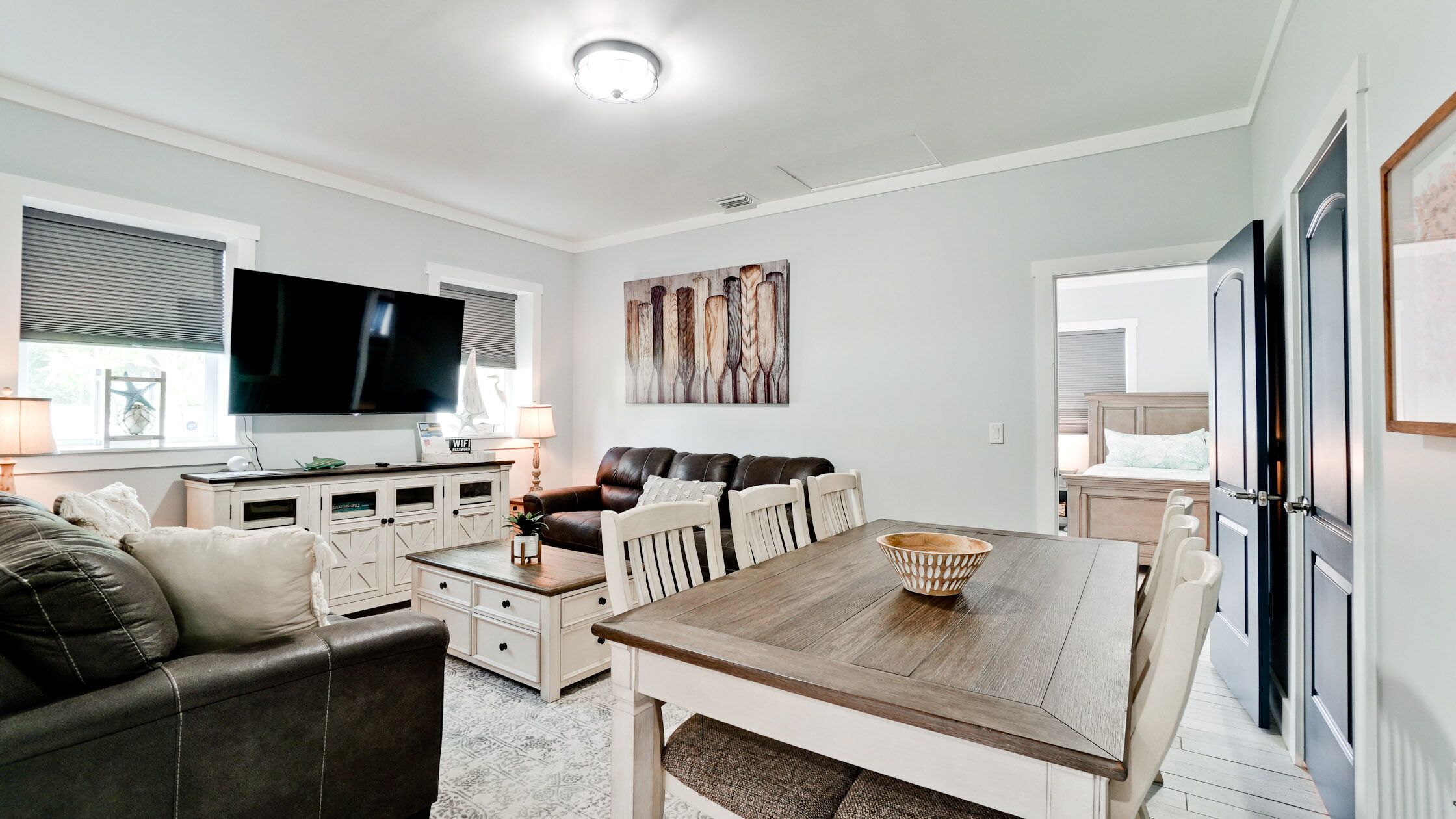 A modern living room with a TV, seating, and a dining area.