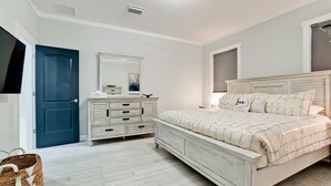 A bedroom with a bed, dresser, and a blue door.
