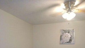 Un dormitorio con cama, ventilador de techo e iluminación de pared.