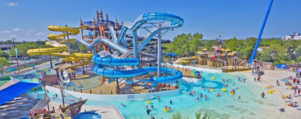 A water park with multiple slides and pools, including a large blue water slide and a smaller yellow one.