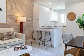 A modern kitchen with white cabinets, a central island, and bar stools. - Genteel Home Feria V (Sevilla)
