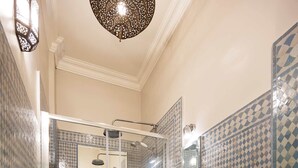 A bathroom with a shower, toilet, and sink, featuring patterned tiles and a wooden toilet seat. - Notting Hill Chic, by Veeve (London)