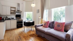 A modern kitchen with white cabinets, a black table, and a grey sofa with decorative pillows. - Notting Hill Chic, by Veeve (London)