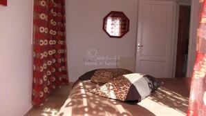 A room with a bed, a patterned curtain, a wall-mounted mirror, and a door. - Superb apartment in residence monaco, sousse (sousse)