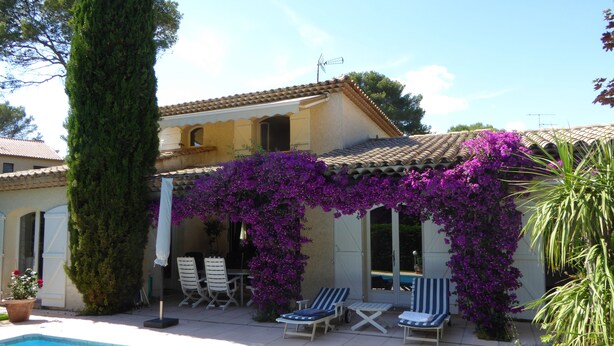 A poolside area with a tiled roof, a pergola covered in purple flowers, and lounge chairs. - BED AND BREAKFAST, private 1st floor in villa  (saint raphael)