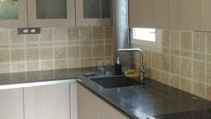 A kitchen with light-colored cabinets, a black countertop, and a tiled backsplash. - BED AND BREAKFAST, private 1st floor in villa  (saint raphael)