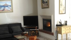 A living room with a sofa, a TV, a fireplace, and a dining table. - BED AND BREAKFAST, private 1st floor in villa  (saint raphael)
