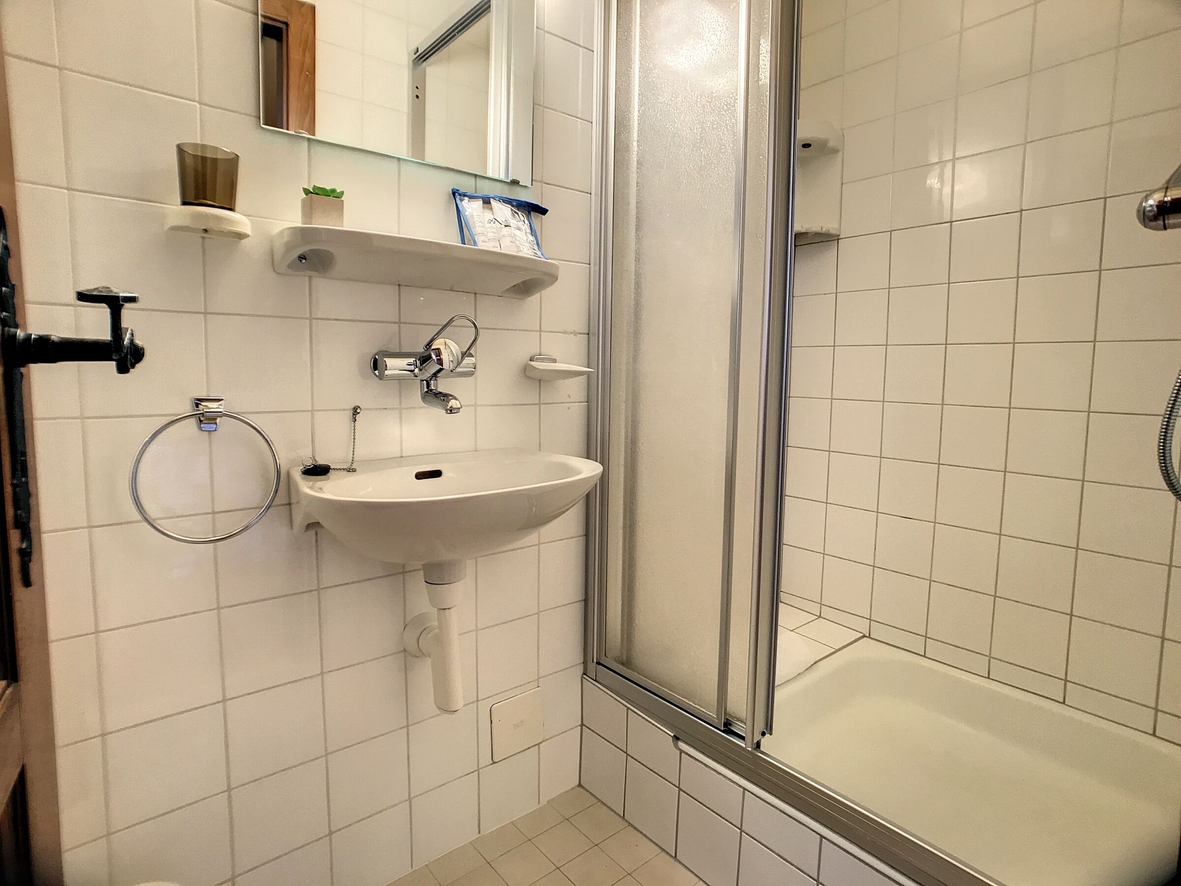 Une salle de bain équipée d’un lavabo, d’un miroir, d’un porte-serviettes et d’une douche.