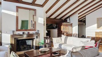 A living room with a fireplace, a large mirror, and a wooden ceiling.