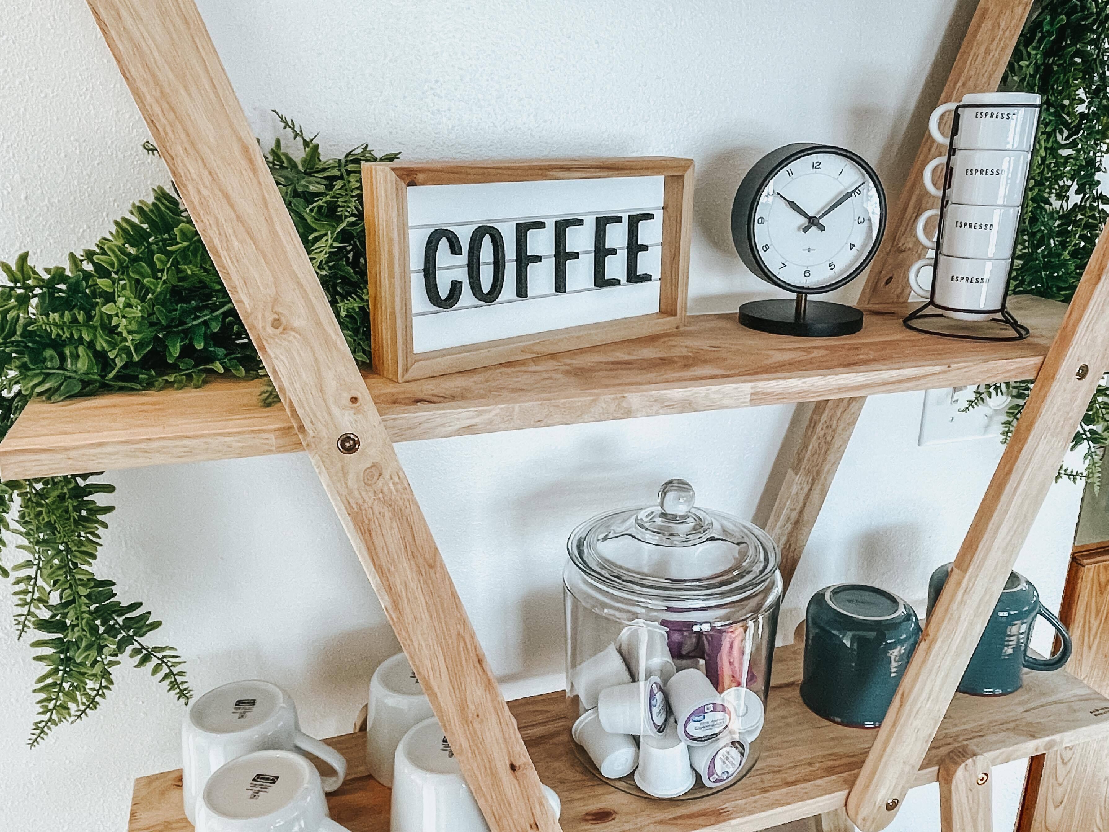 Una repisa de madera con un letrero que dice "COFFEE", un reloj y una cafetera.
