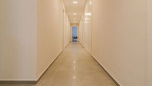 A long, narrow hallway with light-colored walls and a shiny floor, leading to a door at the end. - hilde's house 2 (Scicli)