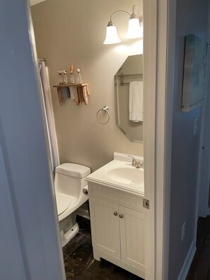 A bathroom with a white sink, a toilet, a mirror, and a shower curtain.