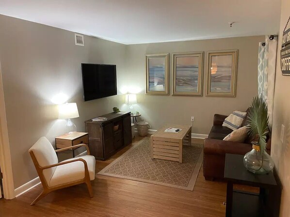 A living room with a sofa, a coffee table, a TV, and framed pictures on the wall.