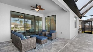 An outdoor patio with wicker furniture and a ceiling fan. - Great Location! 2,444 sq ft canal front villa with heated pool/spa. (Cape Coral)