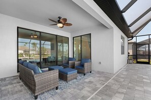 An outdoor patio with wicker furniture and a ceiling fan. - Great Location! 2,444 sq ft canal front villa with heated pool/spa. (Cape Coral)