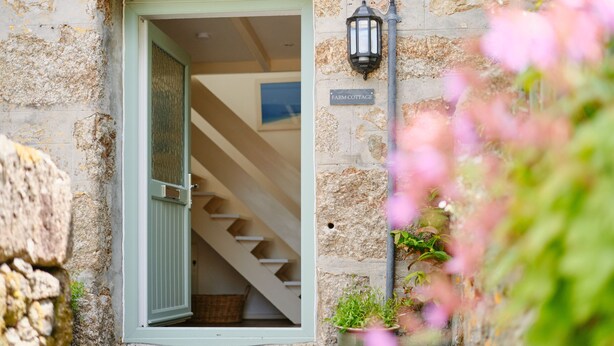 A rustic stone building with a green door and a staircase leading inside. - Farm Cottage, rural St Ives (Cornwall)