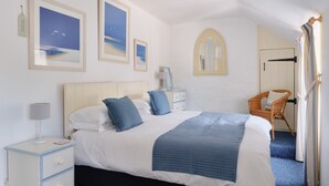 A bedroom with a bed, nightstands, a chair, and artwork on the walls. - Farm Cottage, rural St Ives (Cornwall)