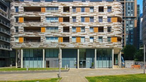 A multi-story building with a modern architectural design, featuring a series of balconies and large windows. - Cosy Studio Apartment in Canary Wharf (London)