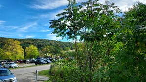 A parking lot with cars and a road leading to a hilly landscape.