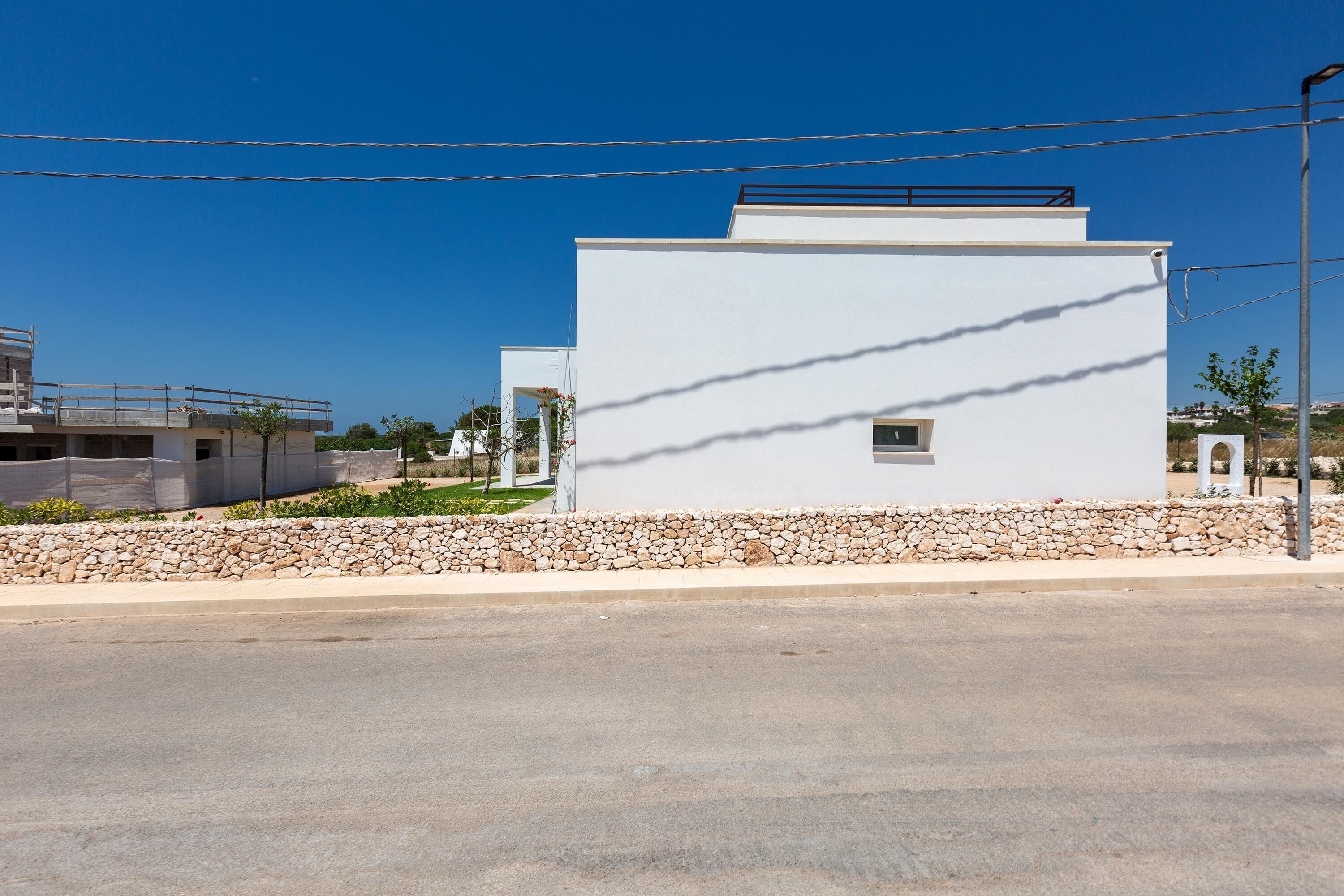 A modern building with a flat roof and a stone wall in front.