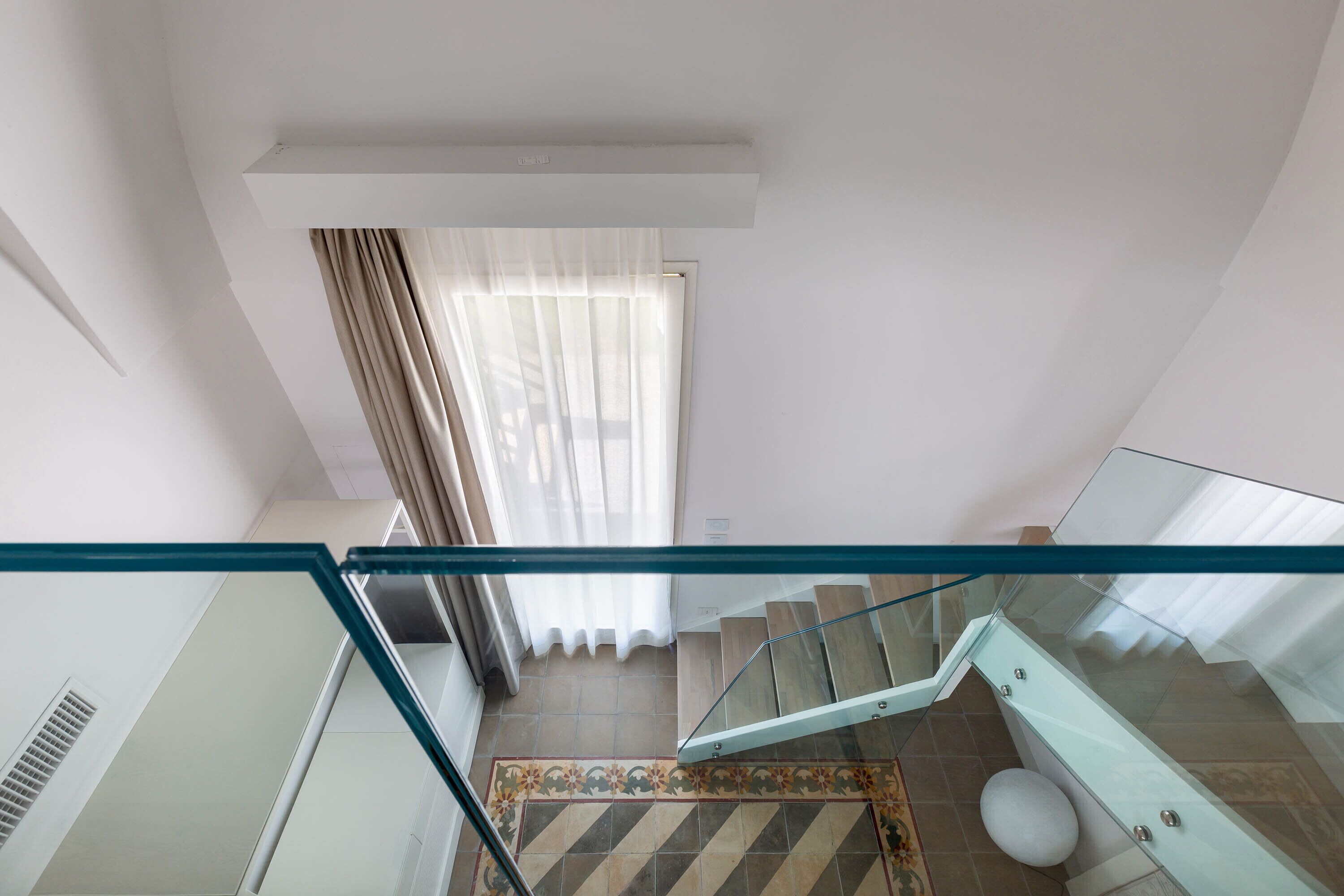 Un intérieur moderne avec une balustrade en verre, un escalier et un sol à motifs.