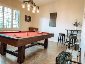 A pool table with a red felt surface, a wooden pool table frame, and a chandelier with multiple lights. - Near State Farm, Spring Training, NASCAR and more-Lakefront with Private Pool!! (Avondale)