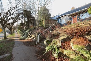 Eine Wohnstraße mit Bürgersteig, Holzzaun und einem Haus mit sichtbarer Treppe.
