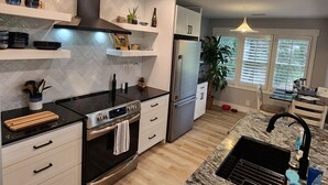 A modern kitchen with a stove, oven, refrigerator, and a sink. - Modern Beach Elegance: The Maples Retreat (Sunset Beach)