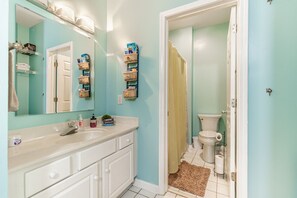 A bathroom with a white vanity, a mirror, a toilet, and a shower curtain.