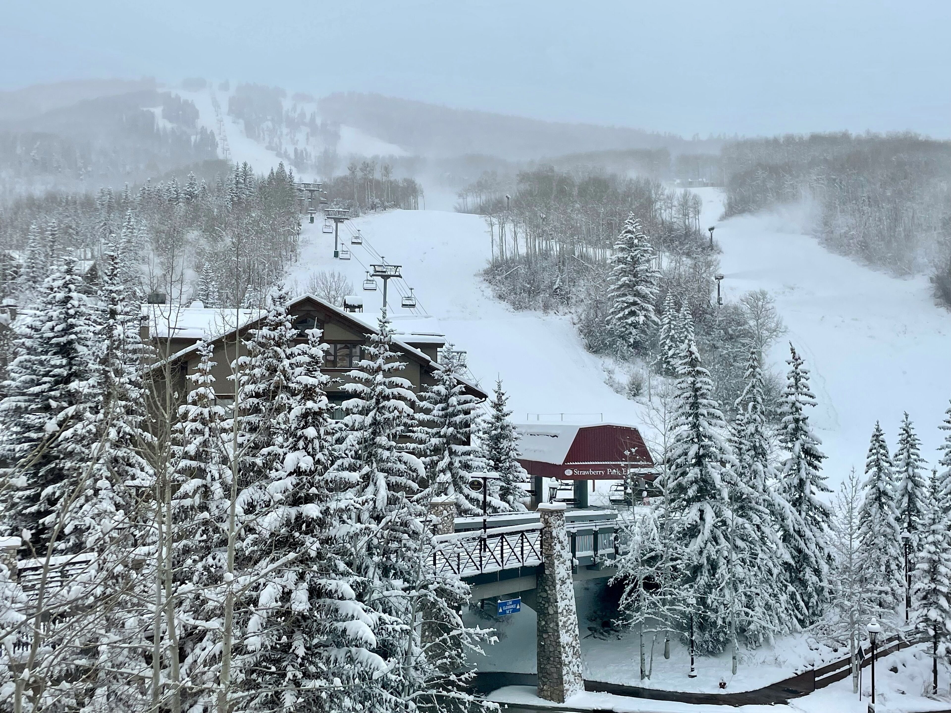 A snow-covered ski resort with a lodge, ski lift, and snowy trees.