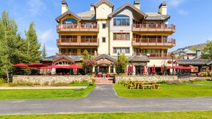 Ein mehrstöckiges Hotel mit zentralem Eingang, Außenbereich zum Sitzen und einer Stein-Fassade.