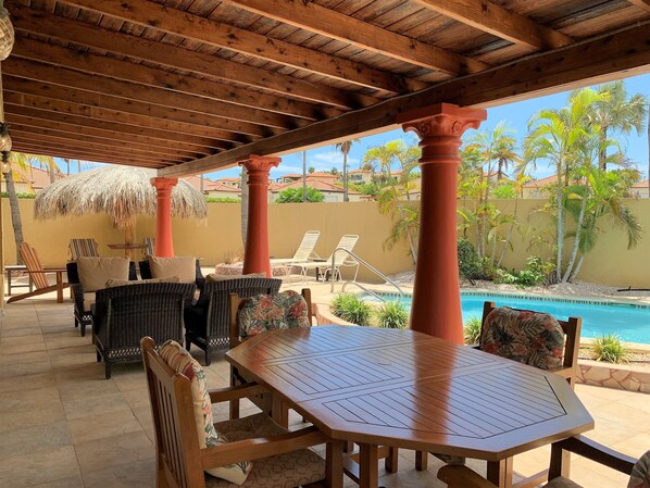 A covered outdoor seating area with wicker furniture and a pool. - Paradise Found @ Tierra Del Sol Golf Course - Private Pool (Noord)
