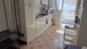Une cuisine moderne avec des meubles blancs, une cuisinière et un four à micro-ondes. On y trouve également un coin repas avec une table et des chaises.