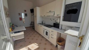 Une cuisine compacte équipée d’une cuisinière à gaz, d’un four à micro-ondes et d’un tableau noir sur lequel est inscrit le mot de passe du réseau Wi-Fi.