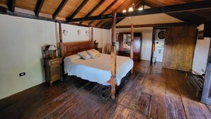 Una cama con dosel en una habitación rústica con vigas de madera y techo inclinado.