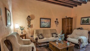 Una sala acogedora con un sofá, sillones, una mesa de centro de madera y un aparador de madera.